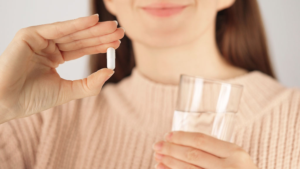 Probiotic capsules beside glass of water on bedside table for senior urinary health routine
